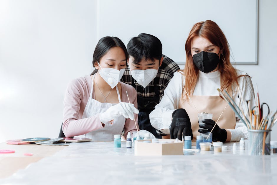 Three people in a resin workshop wearing face masks, focusing on artistic crafts and safety.
