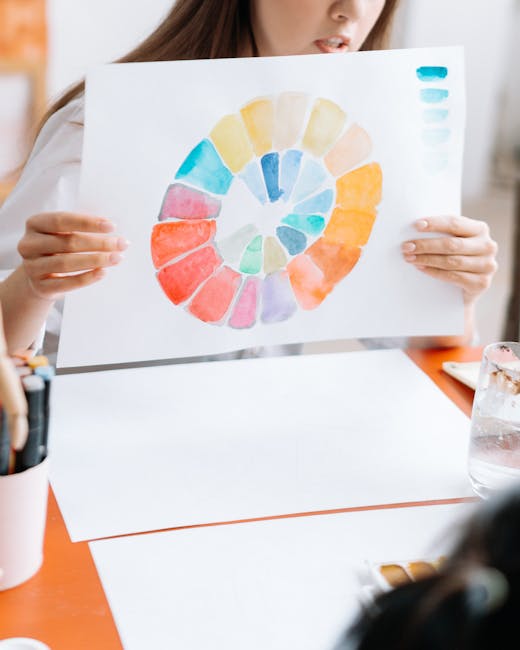 Hands holding a watercolor circle showcasing a full color palette during an art workshop setting indoors.